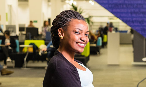 Student sat at desk, smiling at camera