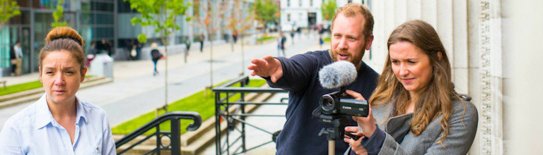 Man demonstrating the use of a video camera to a woman