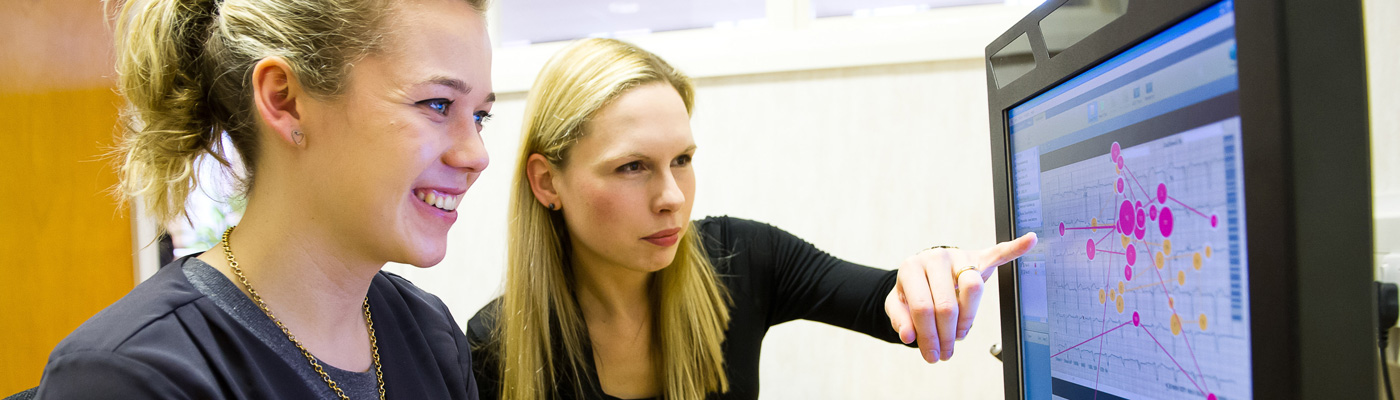 Caroline Jay pointing at computer screen and student smiling